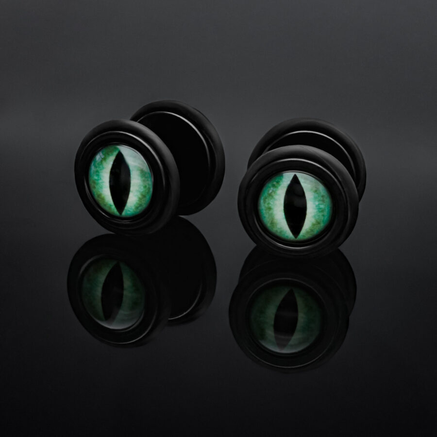 Schwarze Fake Plugs mit grünem Katzenauge auf schwarzem Hintergrund