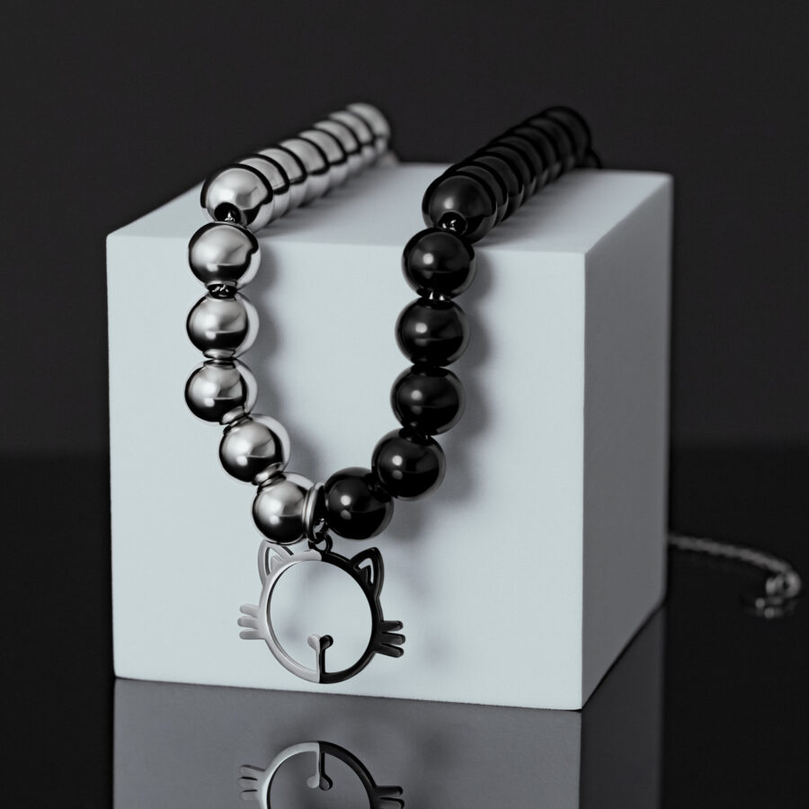 Silber-Schwarze Perlenkette mit Katzenanhänger auf weißem Würfel