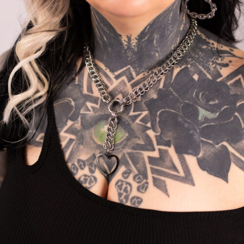 Silberne Choker-Kette mit herzförmigem Anhänger auf tätowierter Haut
