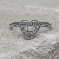 Silberner herzförmiger Ring mit Auge-Motiv auf grauem Stein