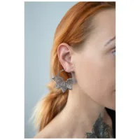 Abey Hoops Ohrringe im Blattdesign Silberne Ohrringe in Form eines Blattes an einem Ohr einer Person mit roten Haaren