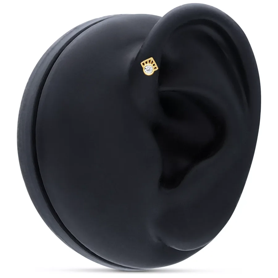 Goldener 14K Piercingaufsatz mit klarem Kristall an einem schwarzen Ohrmodell