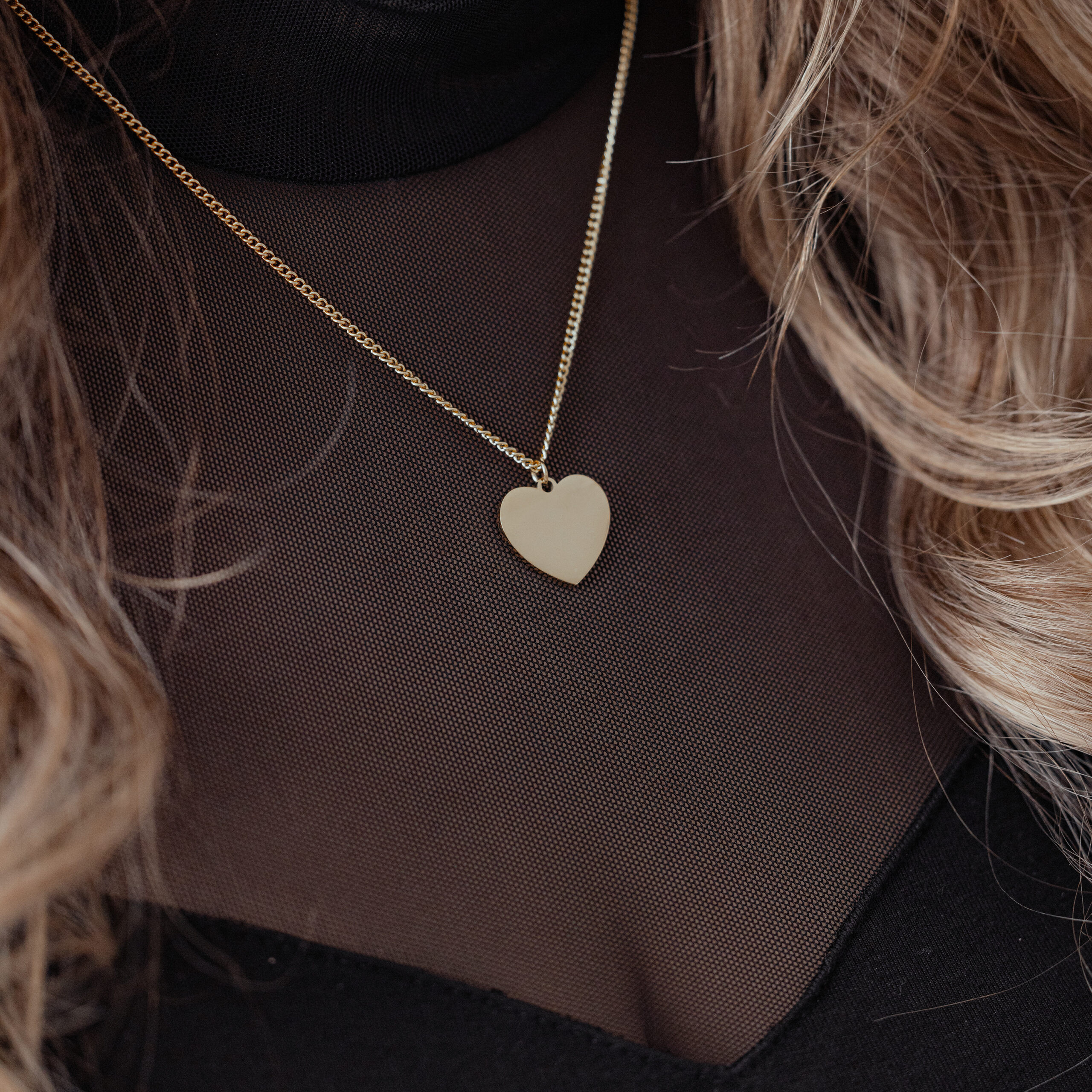 Goldene Herz-Kette aus Chirurgenstahl Goldene Herz-Kette an zarter Kette auf schwarzem Oberteil