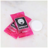 Wildcat Zitronen-Dextrosetabletten 1000 Stk. Zwei pinke Wildcat Zitronen-Dextrosetabletten auf Marmorhintergrund