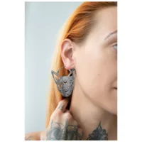 Silberne Sphynx Hoops Ohrringe an einem Ohr mit tätowierter Hand
