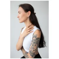 Stilvolle Little Anchor Hoops Ohrringe Frau mit langen Haaren und tätowierten Armen, trägt silberne Little Anchor Hoops Ohrringe