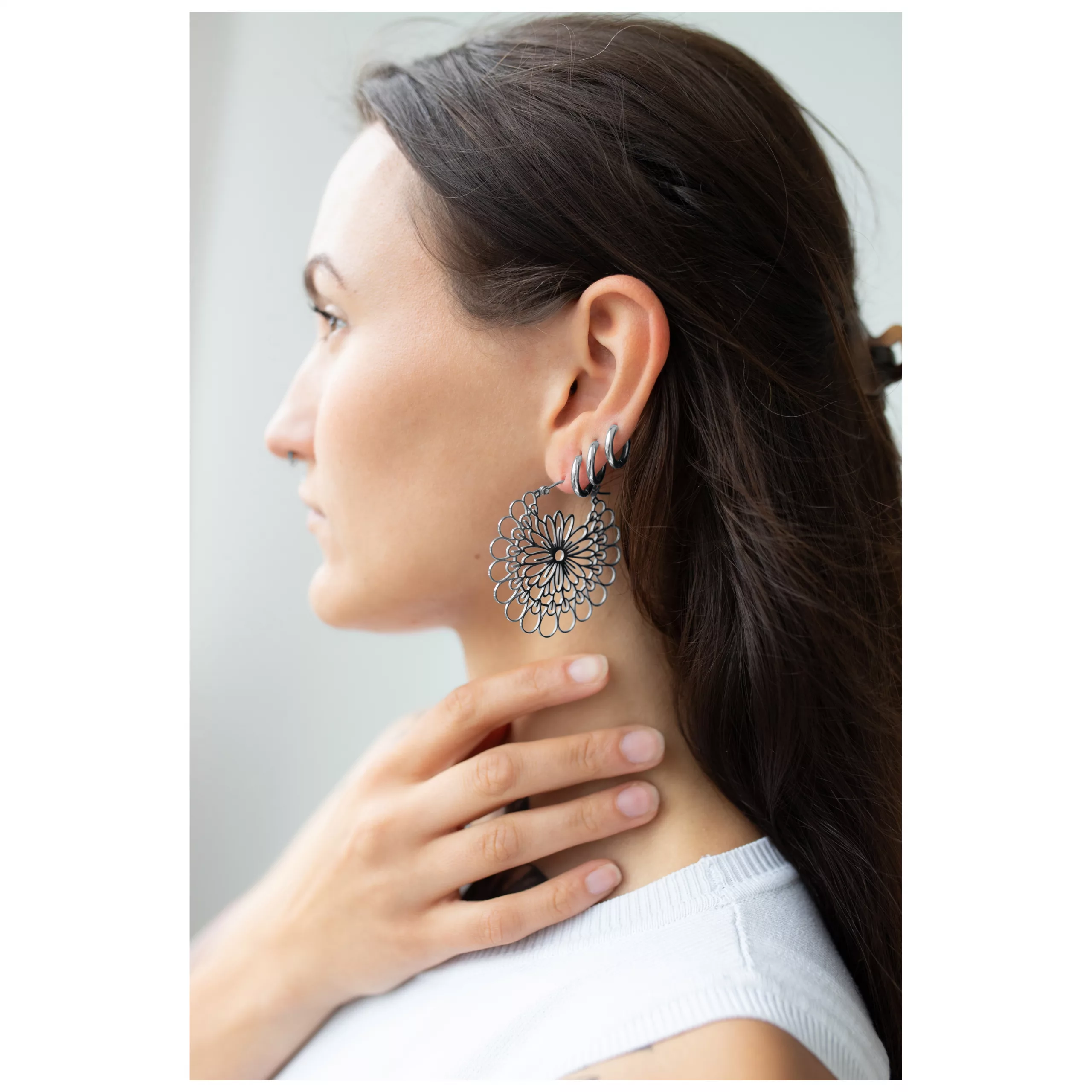 Daisy Hoops Ohrringe in Silber und Schwarz Frau mit Daisy Hoops Ohrringen aus schwarzem und silbernem Chirurgenstahl.