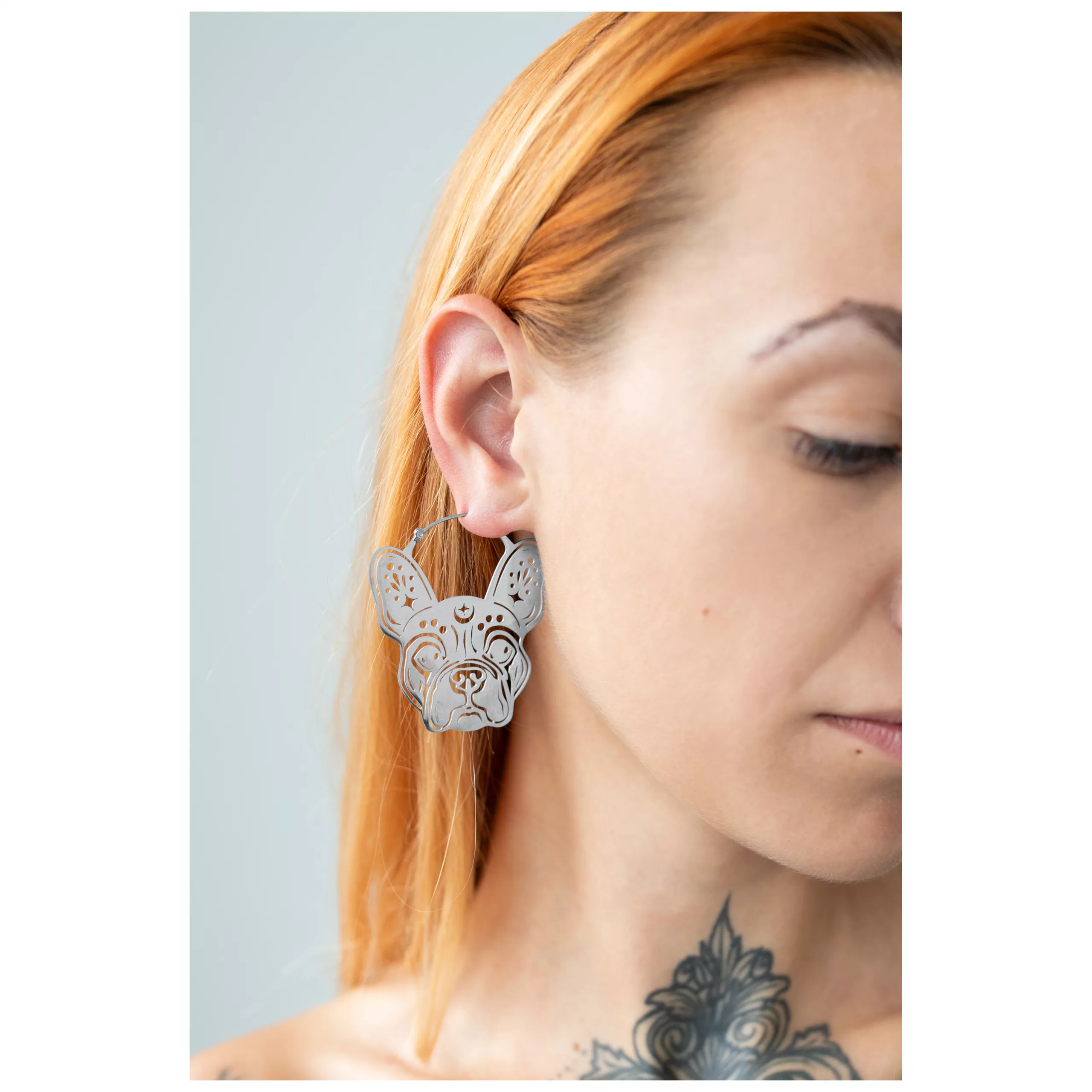 Bulldog Hoops Ohrringe in Silber Silberne Bulldogge-Ohrringe am Ohr einer Frau mit hellen Haaren und Tattoo