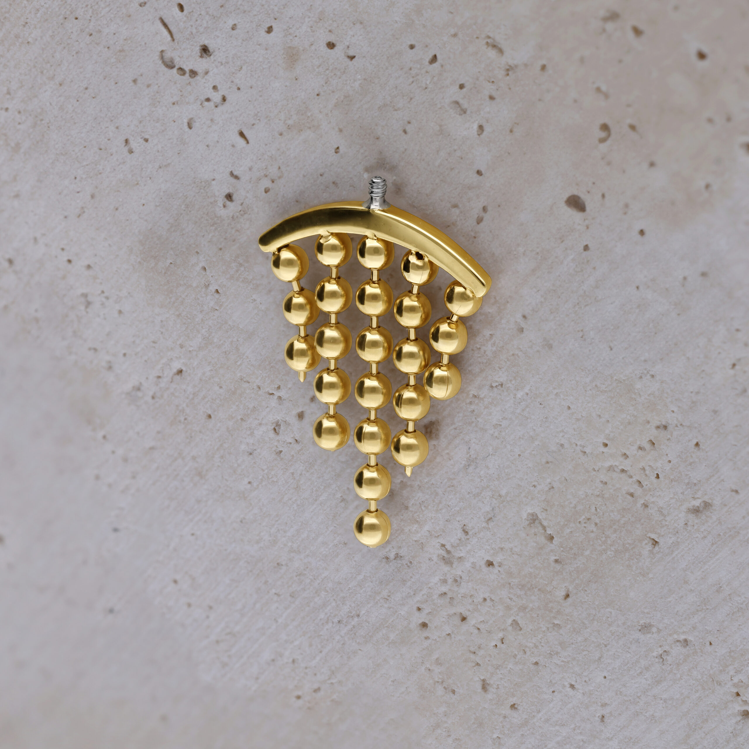 Eleganter Goldaufsatz für Helix-Piercing Goldfarbener Helix-Piercing-Aufsatz mit hängenden Kugeln auf hellem Hintergrund