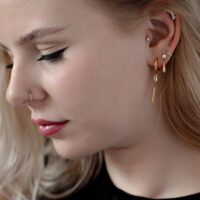 Eleganter Kristall-Piercingaufsatz im Ohr Frau mit mehreren Piercings, darunter ein goldener Kristall-Piercingaufsatz im Ohr.