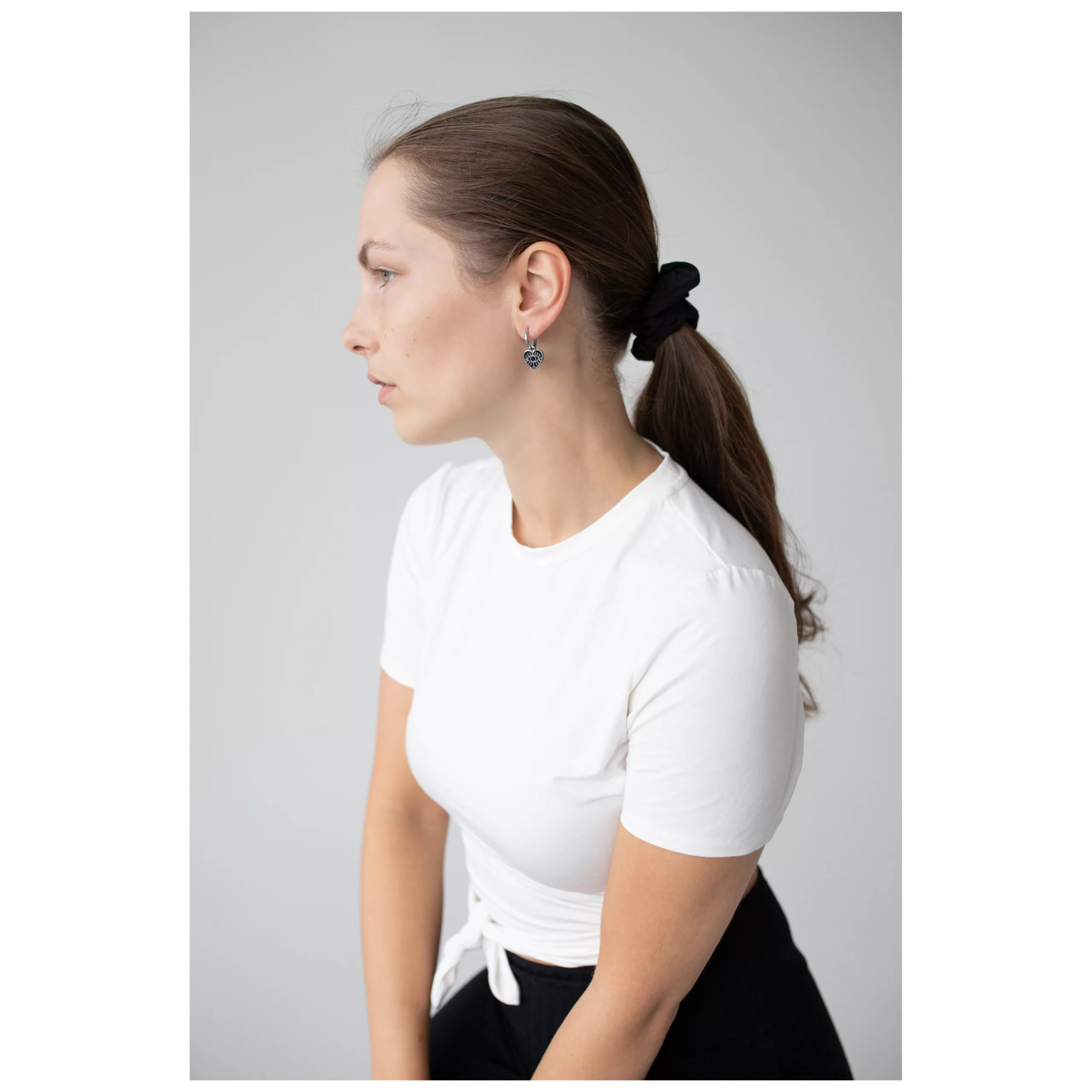 Little Soulmate Hoops am Ohr einer Frau Frau mit weißen Shirt trägt silberne Little Soulmate Hoops vor grauem Hintergrund