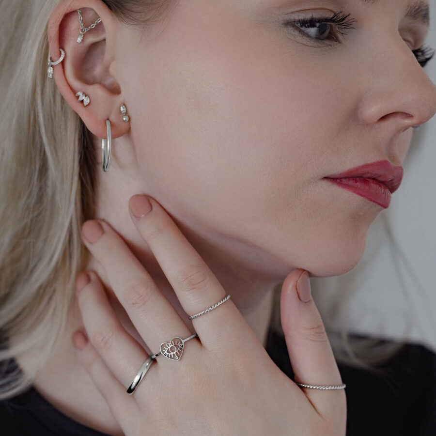 Frau mit mehreren Ohrringen, die einen silbernen Twisted Ring trägt