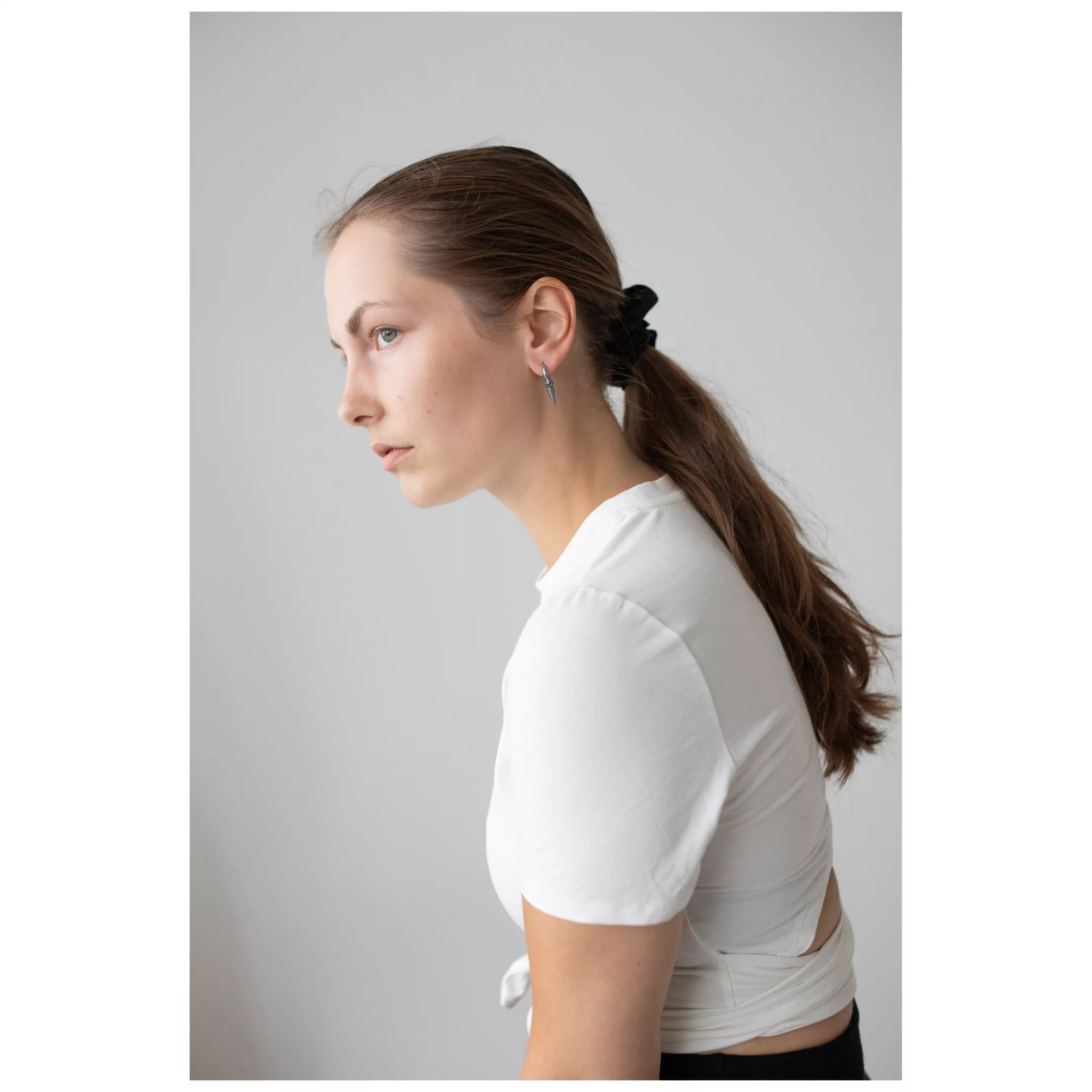 Elegante Spike Ohrringe in Schwarz und Silber Frau mit langen, glatten Haaren trägt Spike Ohrringe aus schwarzem und silbernem Chirurgenstahl, weißes Oberteil.