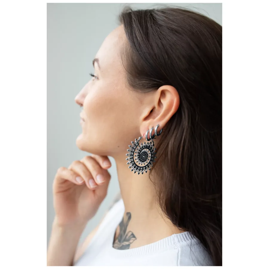 Frau mit silbernen und goldenen Floral Nautilus Hoops vor neutralem Hintergrund