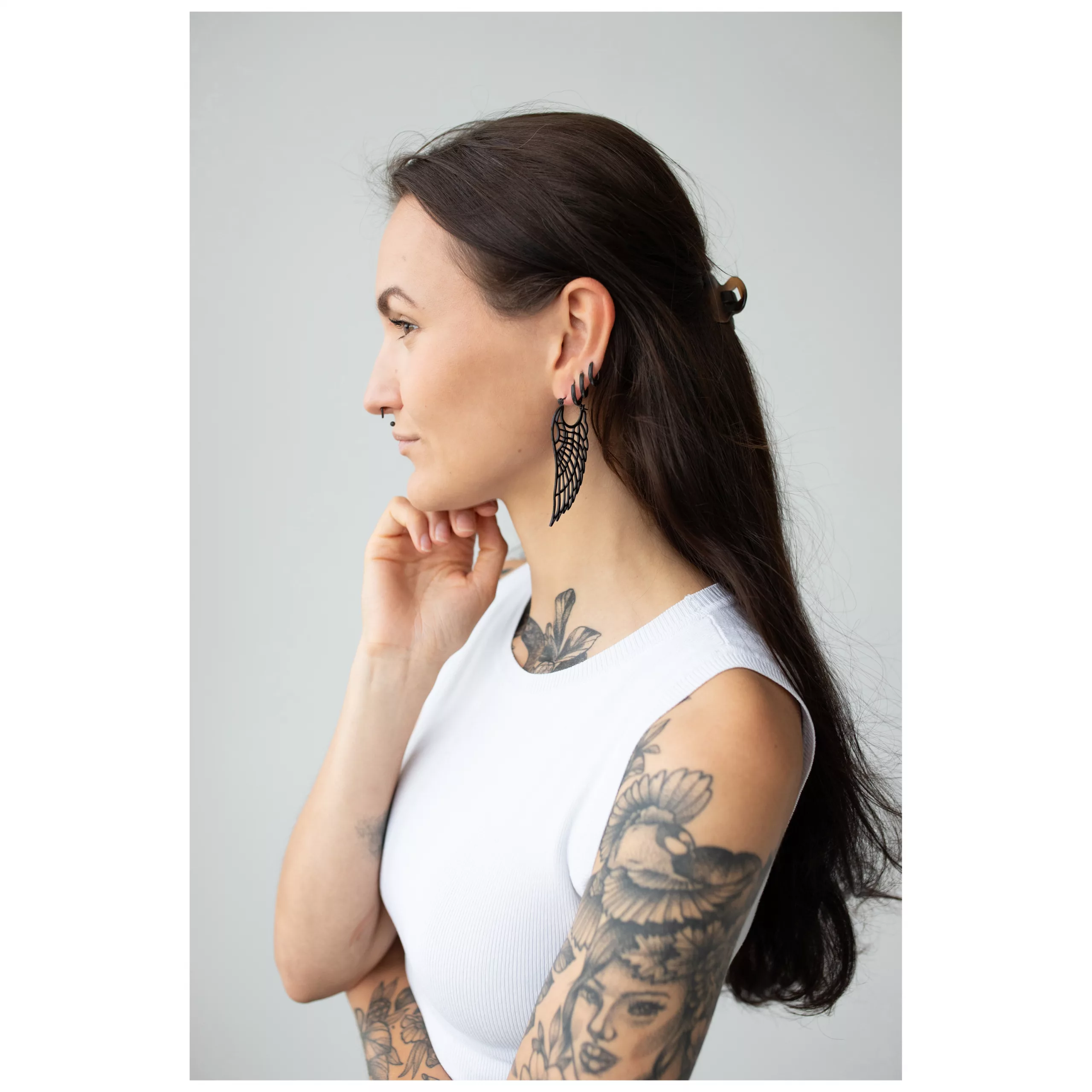 Schwarze Wing Hoops Ohrringe im eleganten Design Frau mit langen dunklen Haaren, trägt schwarze Wing Hoops Ohrringe und weißes Oberteil