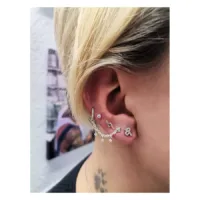 Silberne Piercingkette mit kristallklaren Anhängern am Ohr einer Person