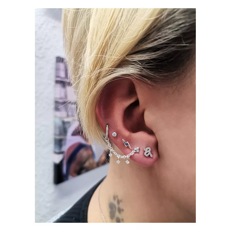 Silberne Piercingkette mit kristallklaren Anhängern am Ohr einer Person