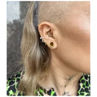 14K Gold Piercingring mit Kristall Nahaufnahme eines Ohres mit mehreren goldenen Piercingringen und Kristallen