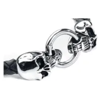 Schädelarmband aus Leder und Chirurgenstahl Schwarzes Lederarmband mit silbernen Schädeln und Ringverschluss vor weißem Hintergrund