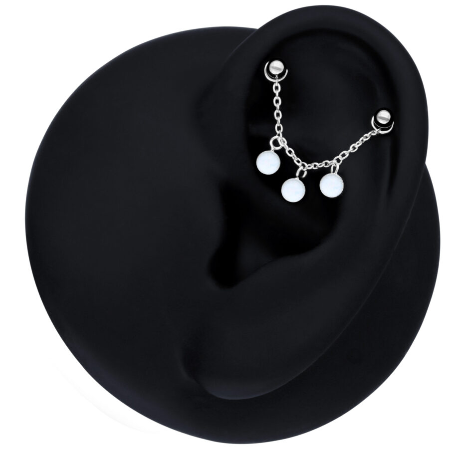 Schwarze Piercingkette mit synthetischem Opal am Ohr auf schwarzem Hintergrund