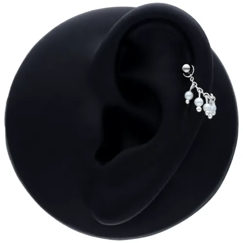 Schwarze Piercingkette mit kleinen Perlen an einem Ohr auf schwarzem Hintergrund