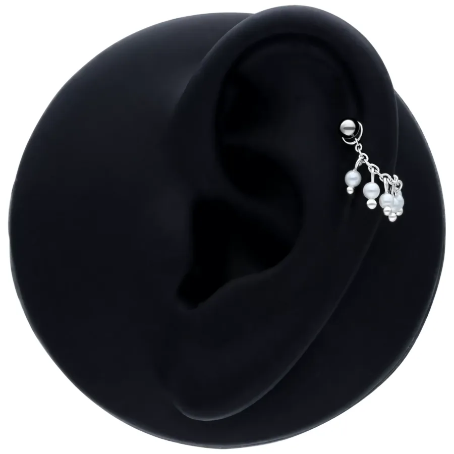 Schwarze Piercingkette mit kleinen Perlen an einem Ohr auf schwarzem Hintergrund