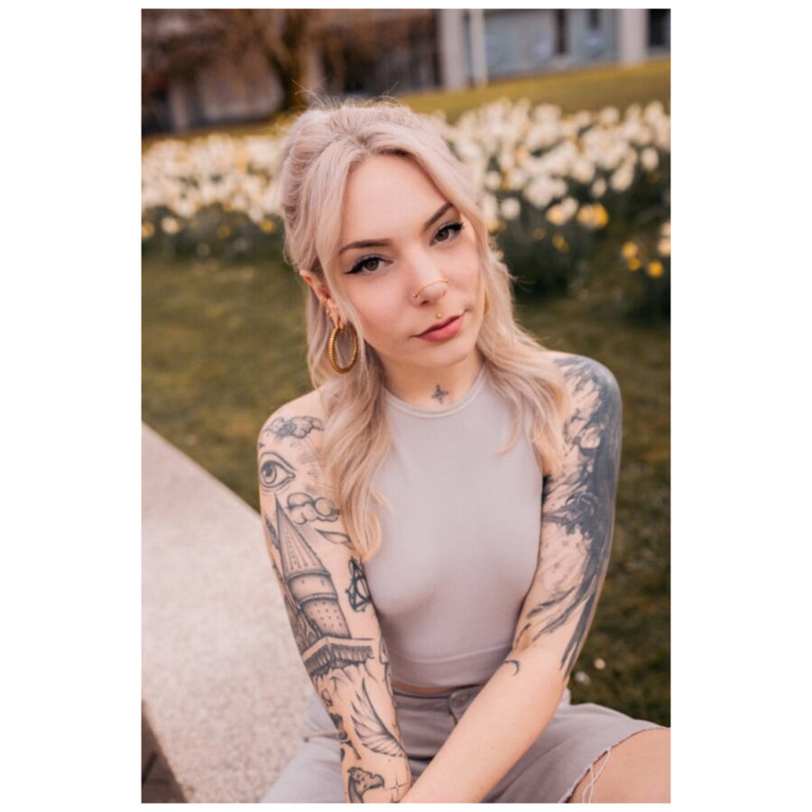 Frau mit Tattoos trägt eine silberne Piercingkette im Park