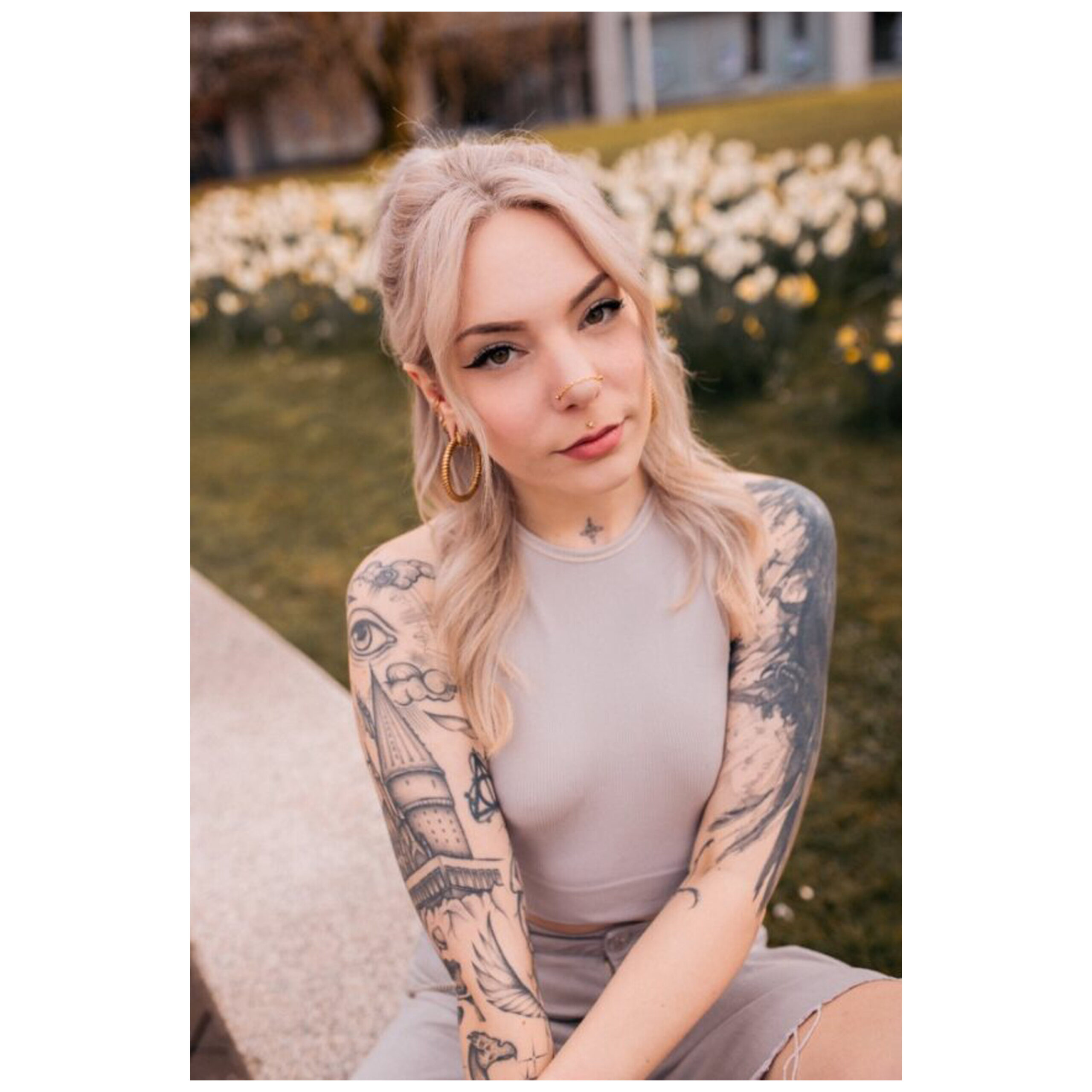 Frau mit Tattoos trägt eine silberne Piercingkette im Park