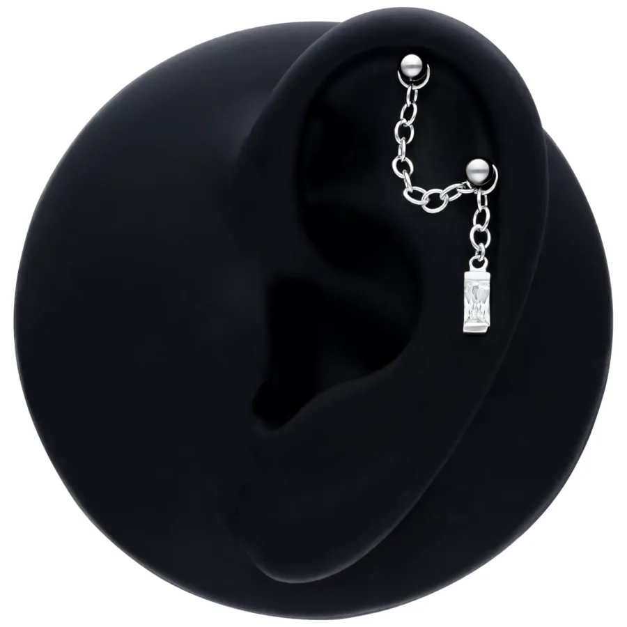 Schwarze Piercingkette mit Hänge-Baguette-Kristall an einem Ohrmodell