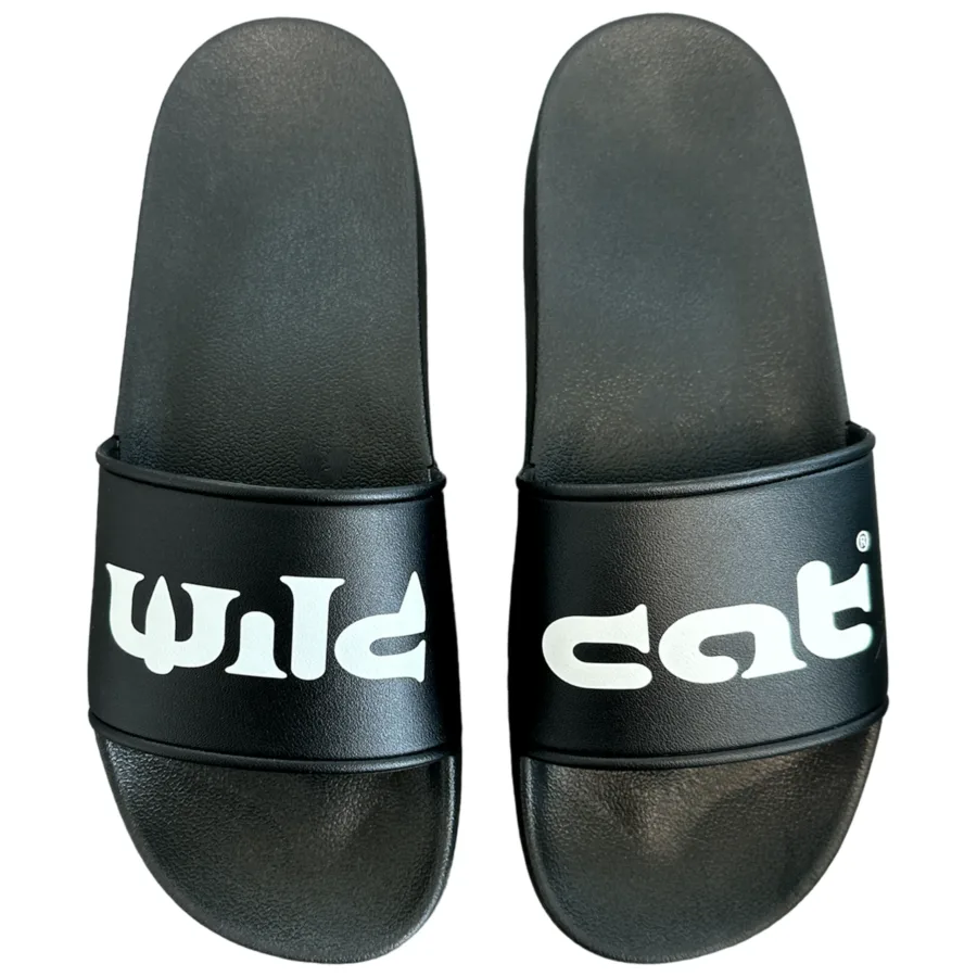 Schwarze Wildcat Sandalen aus PVC mit weißem Logo auf weißem Hintergrund