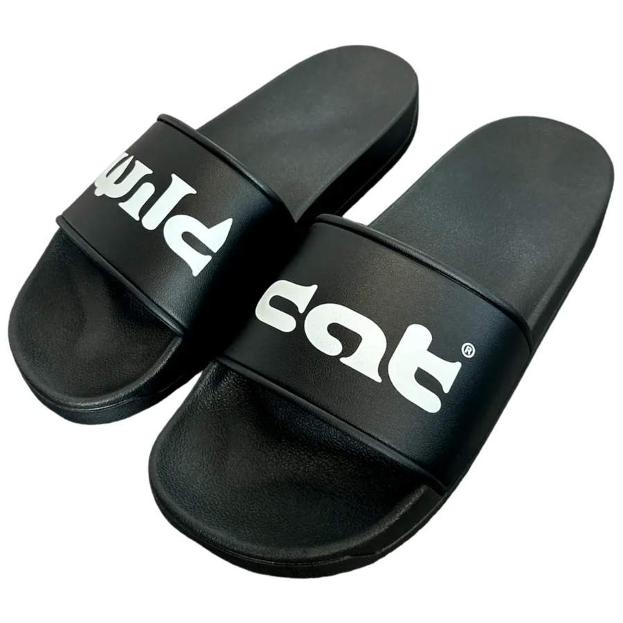Schwarze PVC-Slides mit weißem Wildcat-Logo auf neutralem Hintergrund