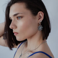 Elegante Blumen-Ohrstecker in Silber Frau mit kurzen Haaren trägt auffällige silberne Blumen-Ohrstecker