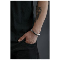 Silberfarbenes Bubble Armband am Handgelenk Silberfarbenes Bubble Armband an einem tätowierten Handgelenk vor grauem Hintergrund