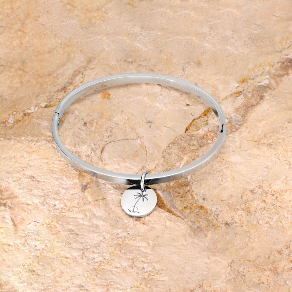 Silbernes Armband mit rundem Anhänger auf beigem Steinuntergrund