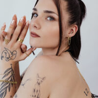 Gloria Piercing Aufsatz in Gold Frau mit goldenen Piercings und Tattoos, seitliches Profil