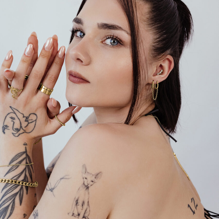 Frau mit goldenen Piercings und Tattoos, seitliches Profil