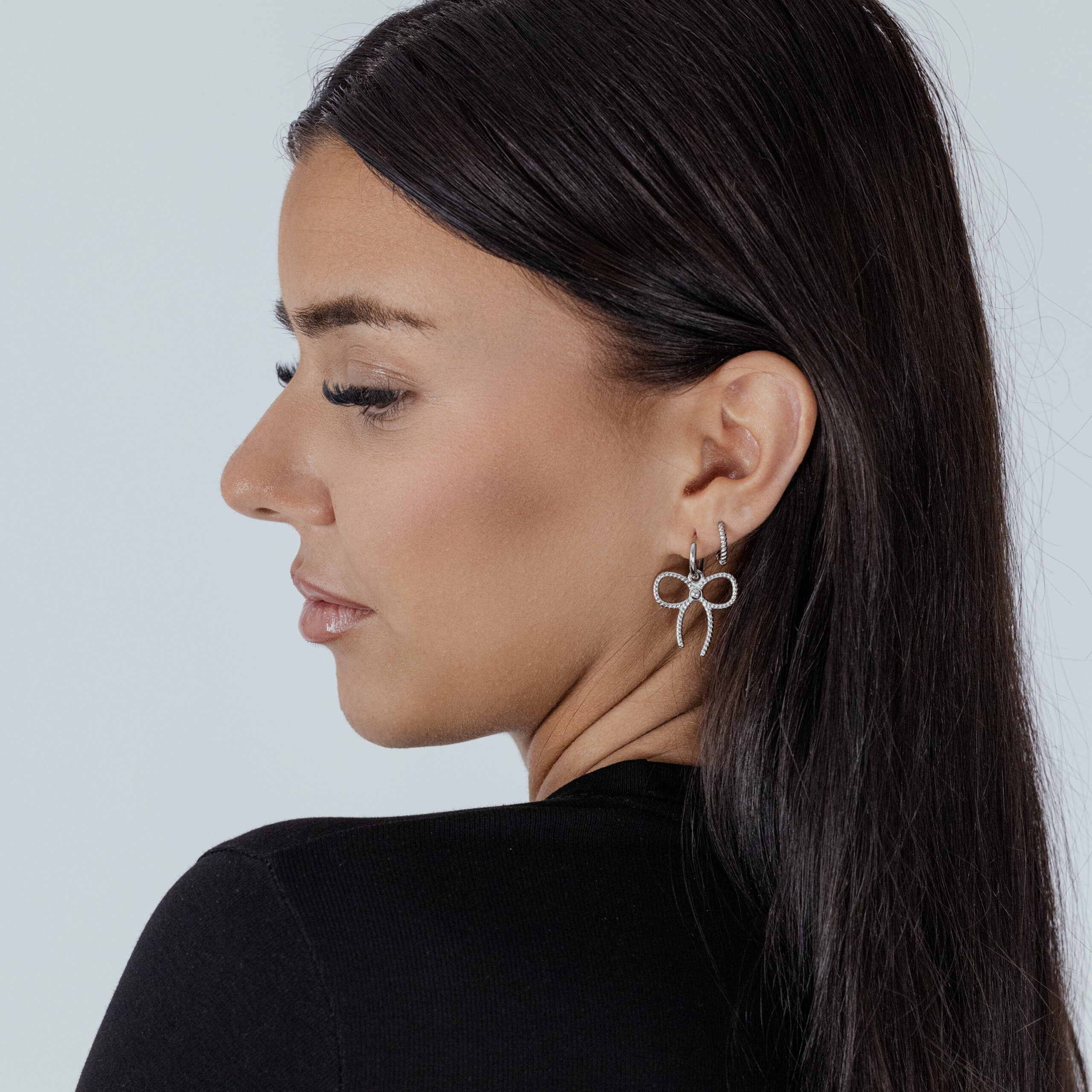 Stilvolle Little Twisted Bow Hoops in Silber Frau mit silbernen Little Twisted Bow Hoops vor hellem Hintergrund