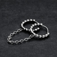 Zwei verbundene schwarze Huggie Piercingringe mit Kugeln auf dunklem Hintergrund