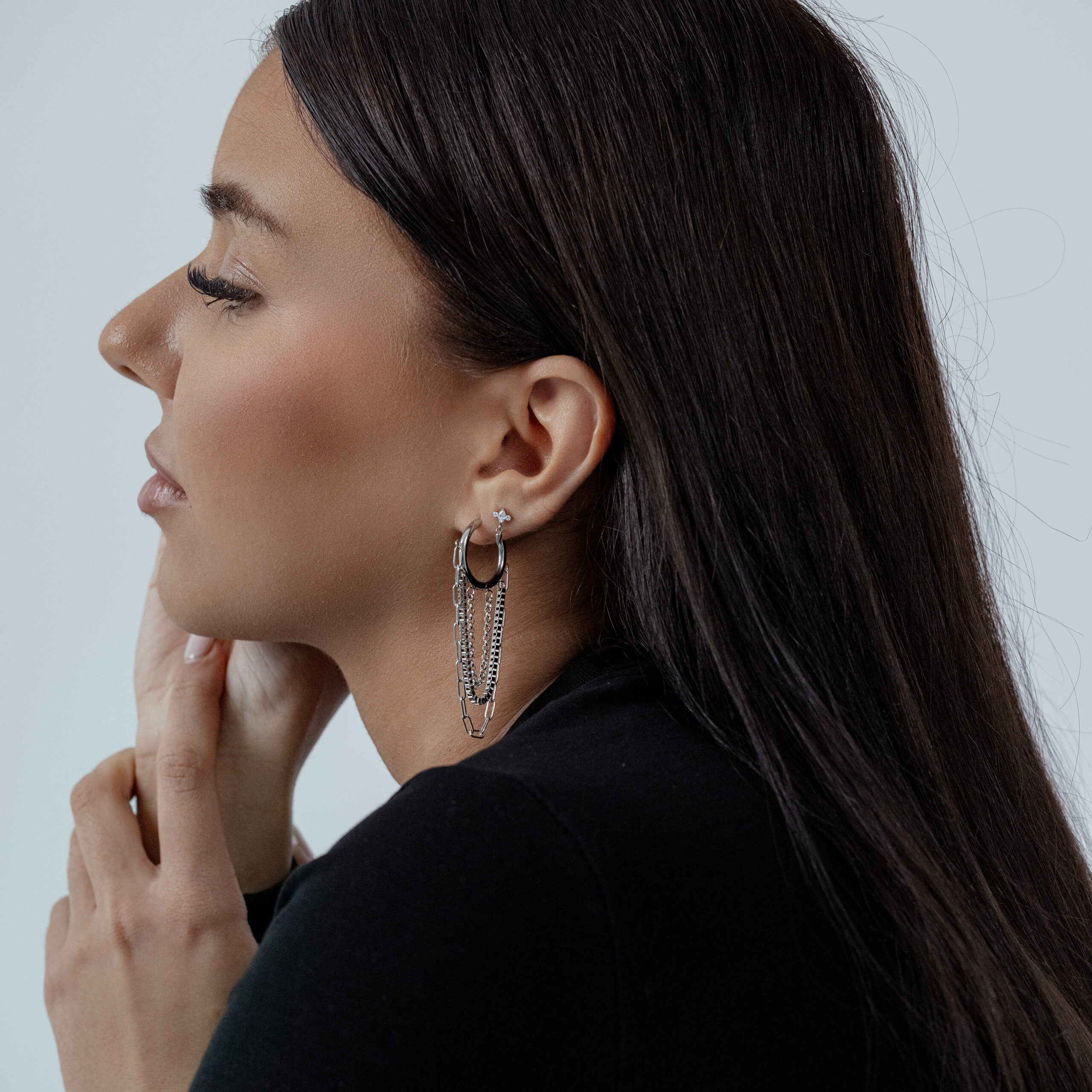 Moderner Multilayer Chain Hoops Ohrschmuck Frau mit schwarzen Haaren trägt silberne Multilayer Chain Hoops auf hellem Hintergrund