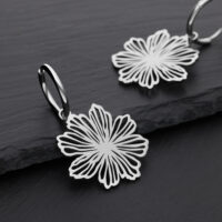 Zwei silberne Ohrringe mit Blumenmuster auf schwarzem Hintergrund