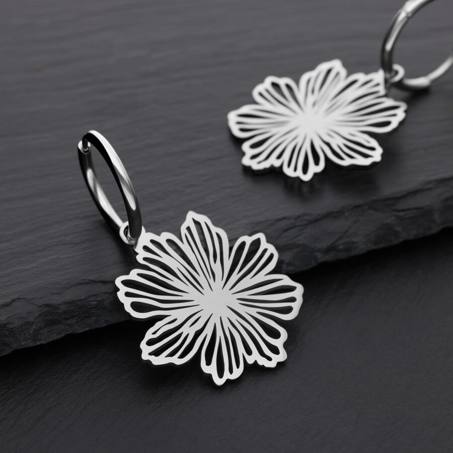 Zwei silberne Ohrringe mit Blumenmuster auf schwarzem Hintergrund