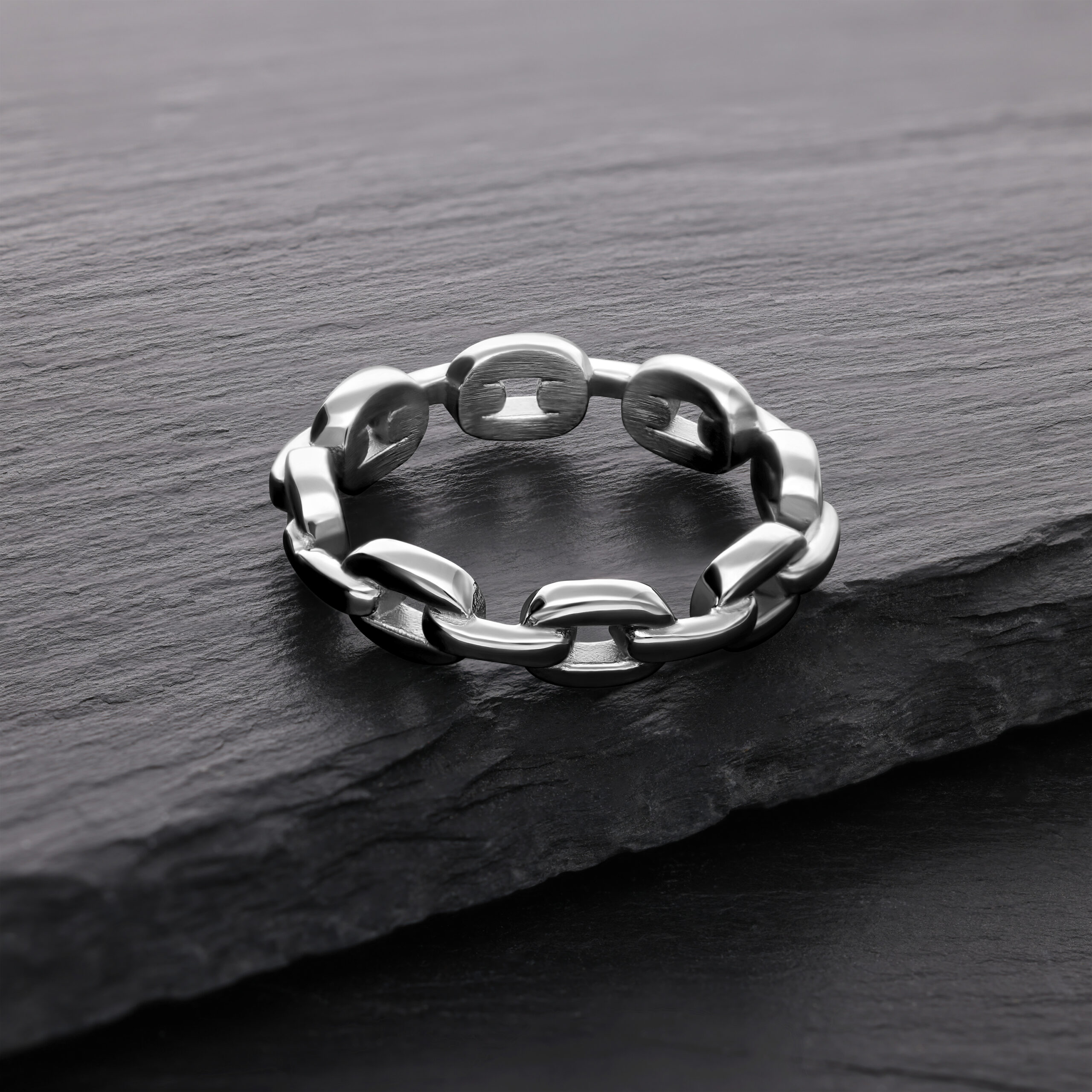 Silberner Link Chain Ring aus Chirurgenstahl Silberner Link Chain Ring aus Chirurgenstahl auf dunklem Stein