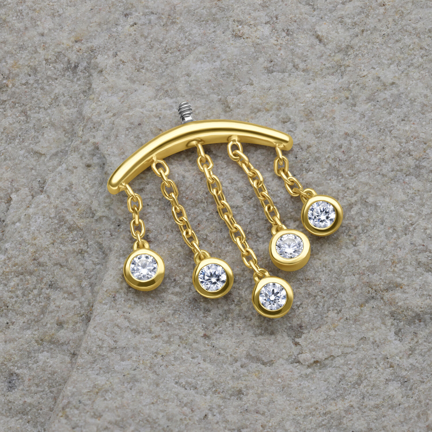 Goldener Piercing-Aufsatz mit fünf klaren Kristalltropfen auf grauem Hintergrund