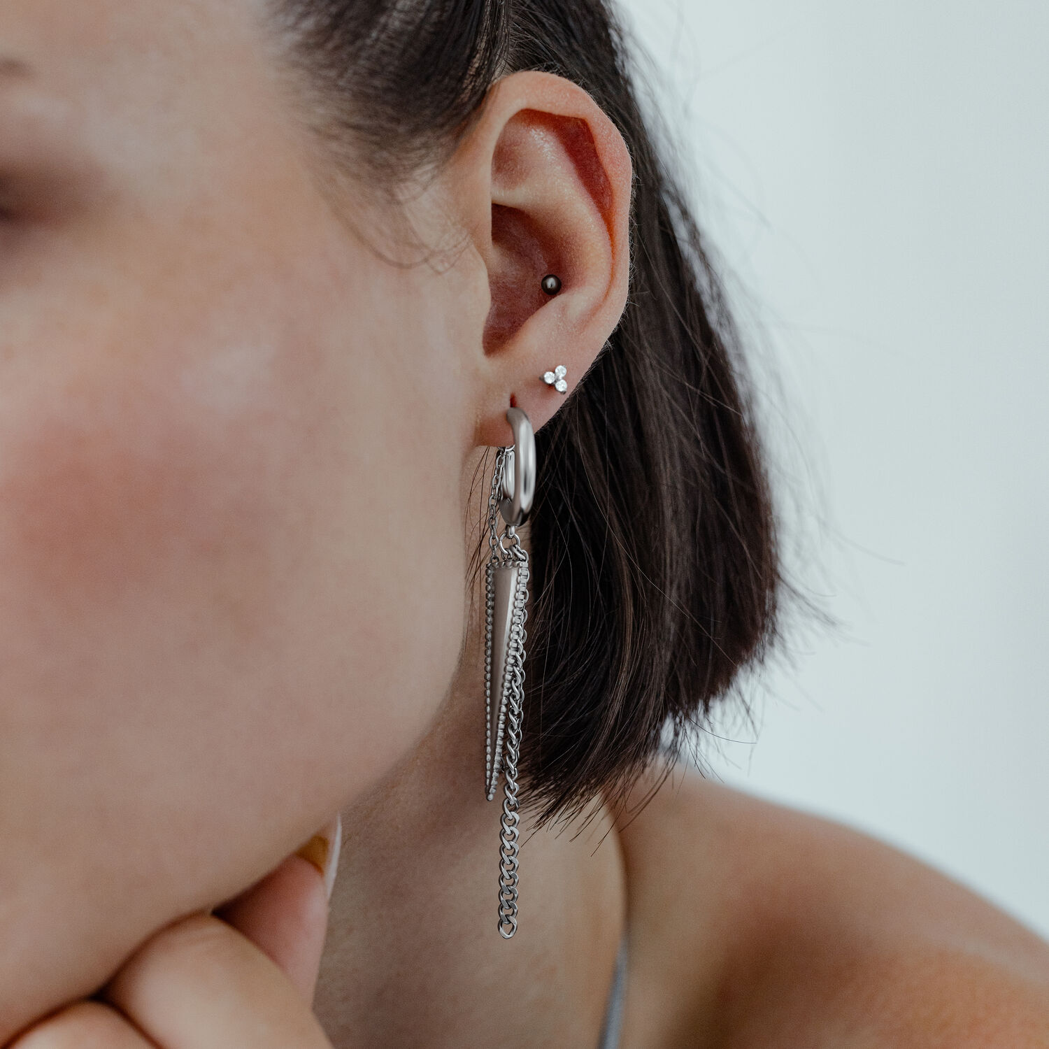 Silberne Triangle Ohrstecker am Ohr Silberne Triangle Ohrstecker am Ohr einer Frau mit kurzen Haaren vor hellem Hintergrund