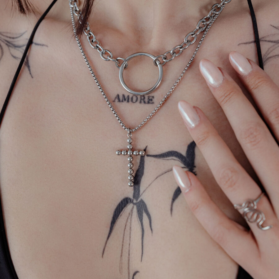 Silberne Bubble Cross Halskette an einer Frau mit Tattoos, Nahaufnahme