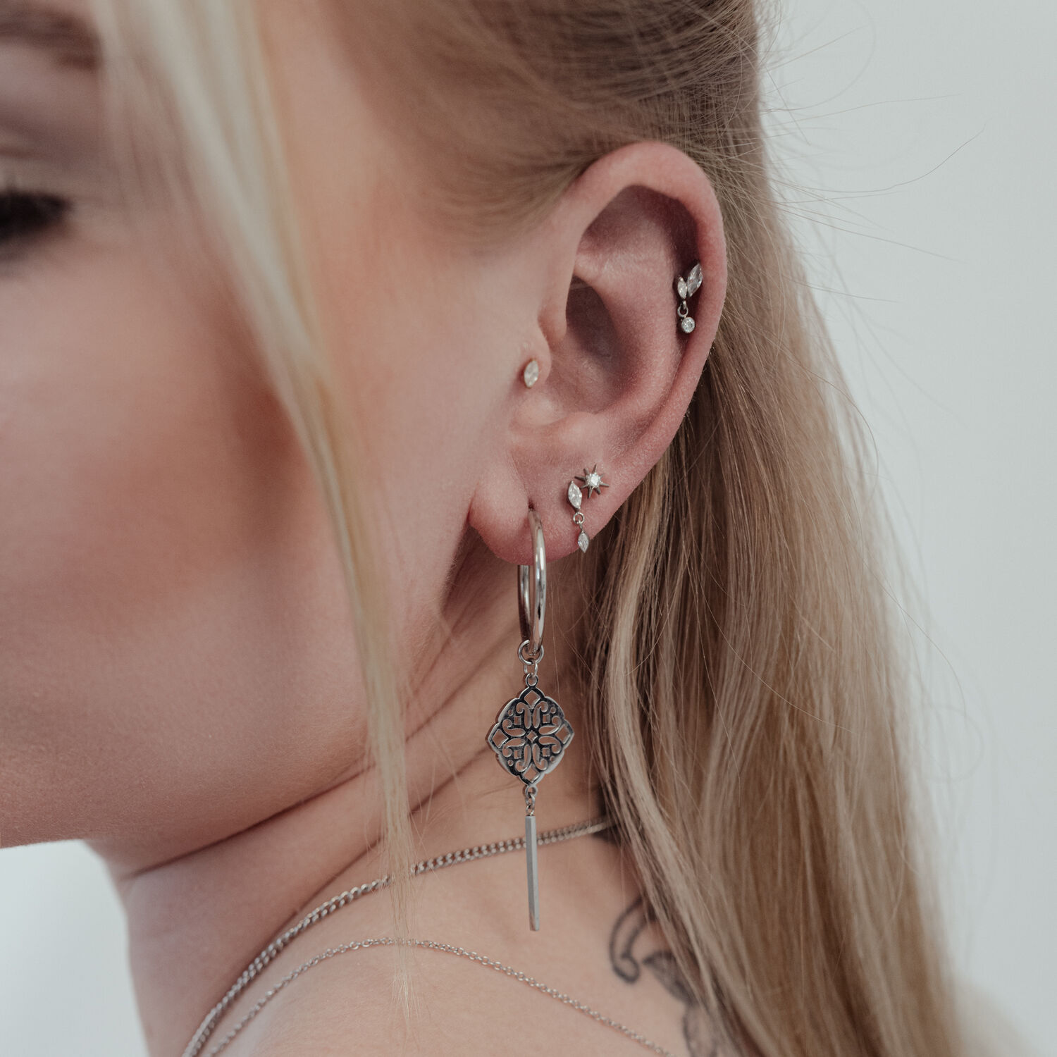 Push Fit Kristall Stern Aufsatz am Ohr Nahaufnahme eines Ohres mit mehreren Piercings, darunter ein großer, silberner Push Fit Kristall Stern Aufsatz.