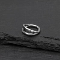 Doppelreihiger Silber Clicker Piercing Ring Silberner doppelreihiger Clicker Ring aus Titan auf schwarzem Hintergrund