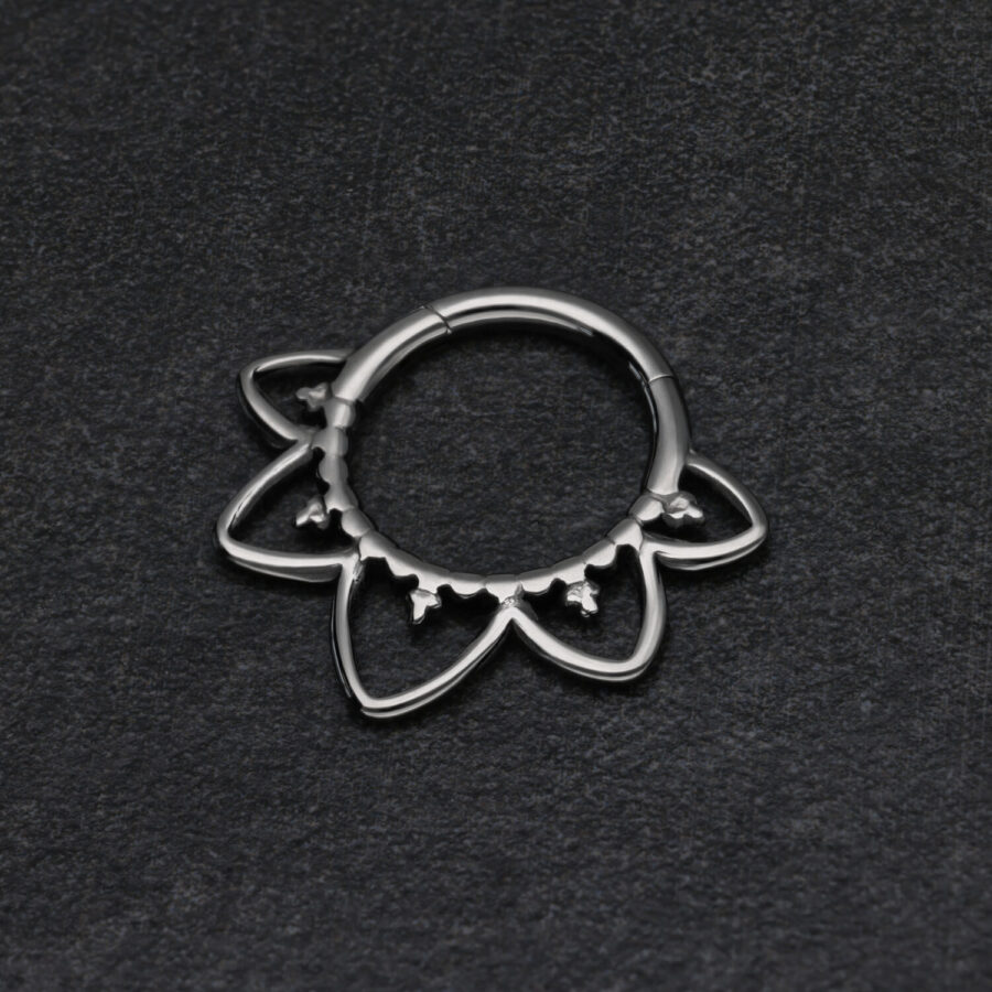 Schwarzer Septum Clicker in Blütenform auf dunklem Hintergrund