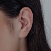 14K Gold Moissanite Aufsatz im Ohr Nahaufnahme eines Ohres mit 14K Gold Moissanite Aufsatz auf neutralem Hintergrund