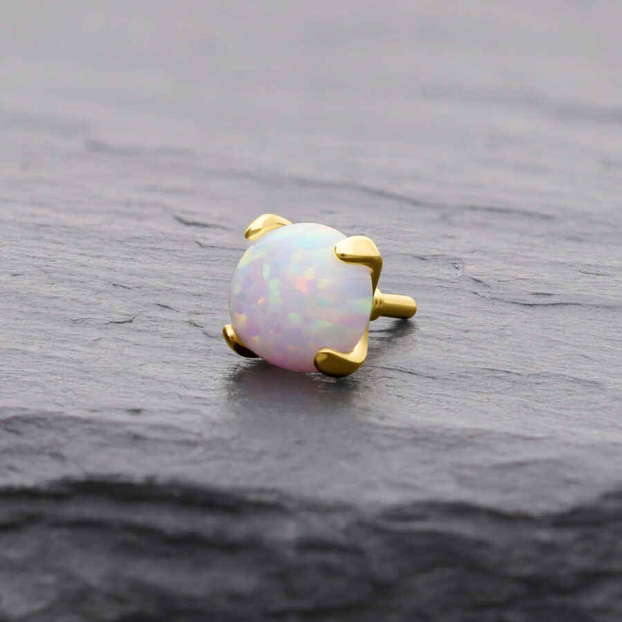 Runder 14K Goldaufsatz mit synthetischem Opal auf grauem Hintergrund